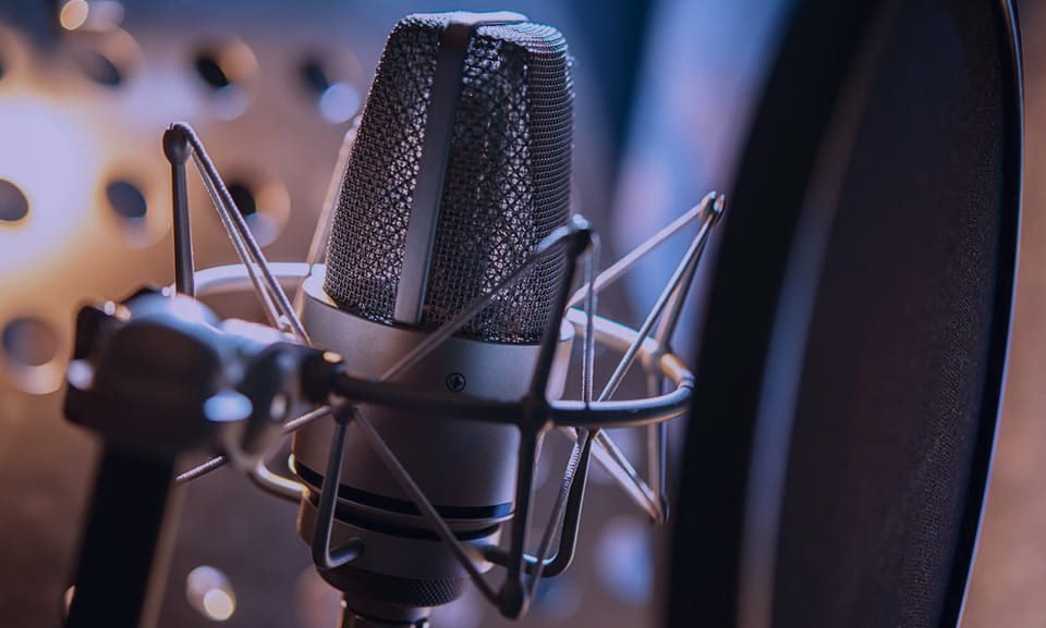 Condenser microphone lit blue behind a pop filter